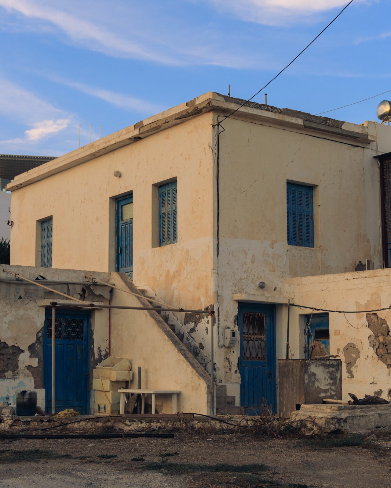 A weathered island house with blue doors and an external stair, Greece