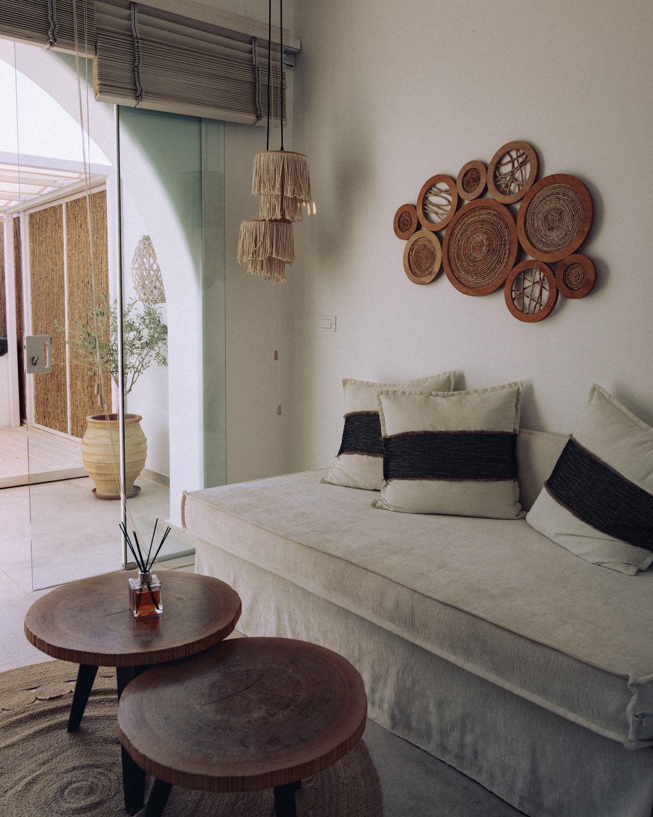A serene minimalist interior — a white daybed and woven wall baskets, Greece