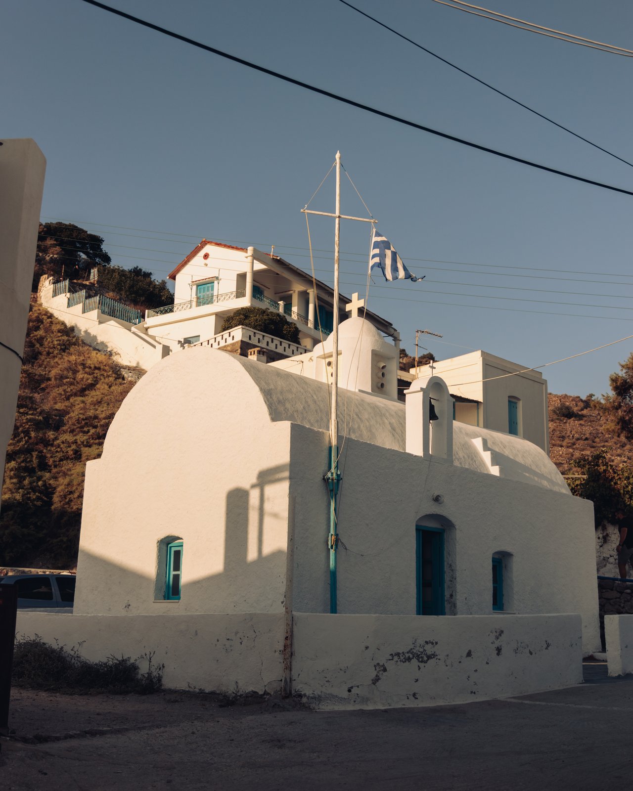A whitewashed island church flying a Greek flag on a hillside, Greece