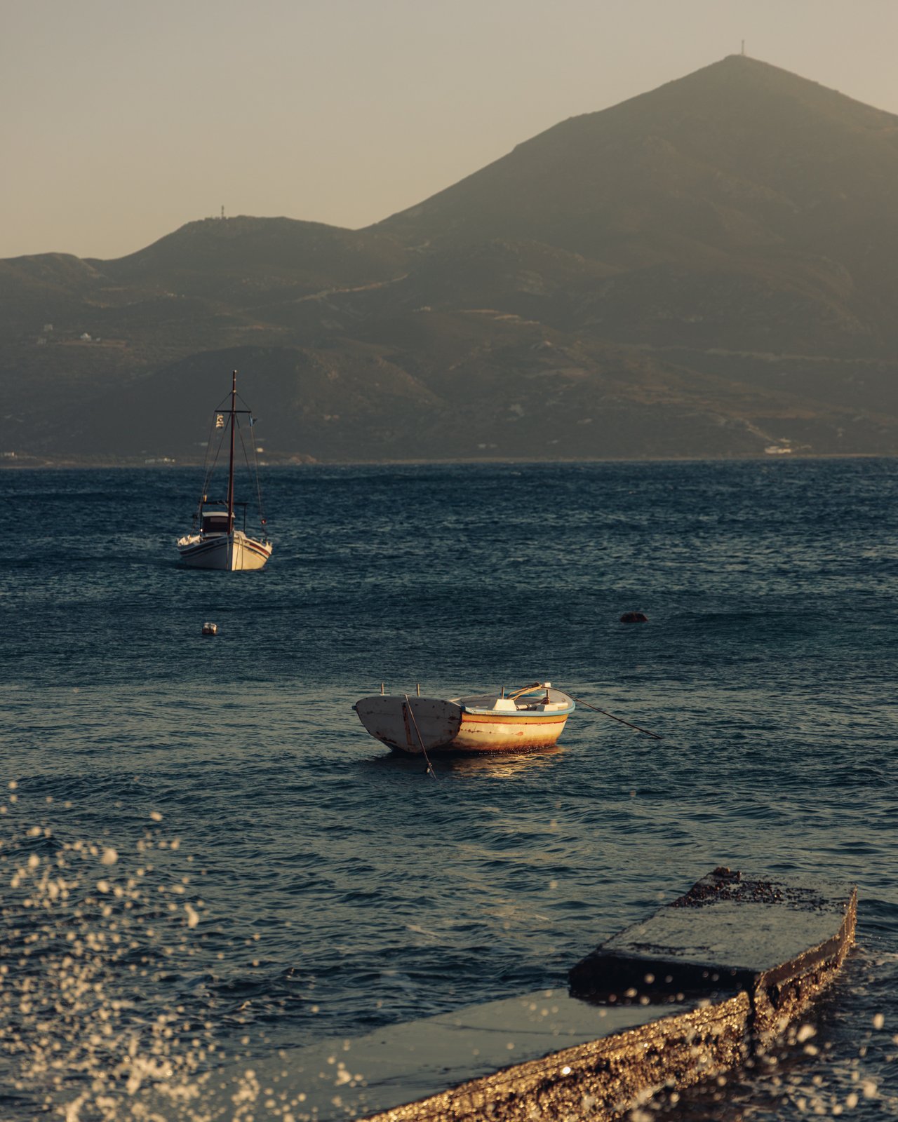 Fishing boats moored in a calm bay at dusk, mountains behind, Greece