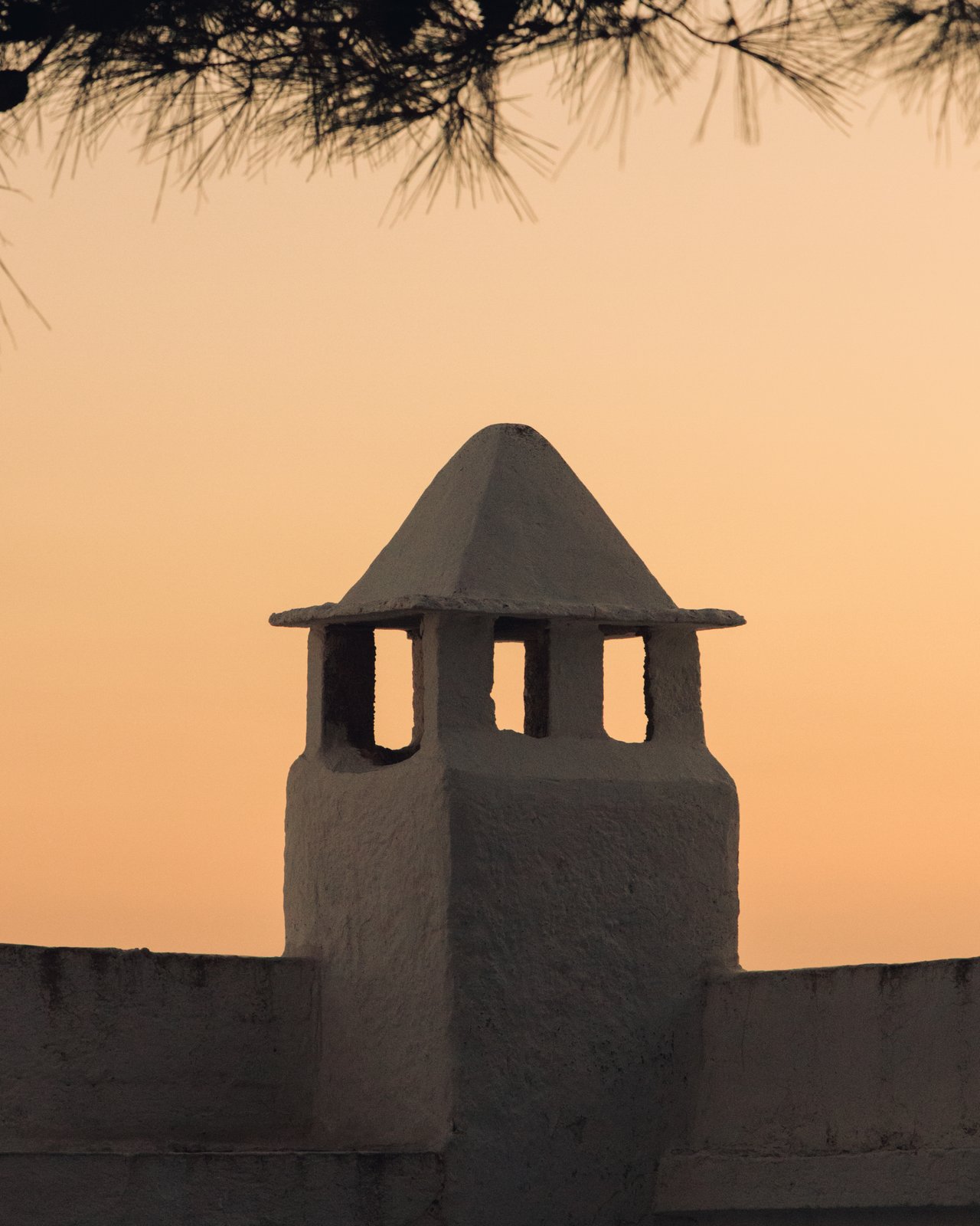 A Cycladic chimney silhouetted against a golden sunset, Greece