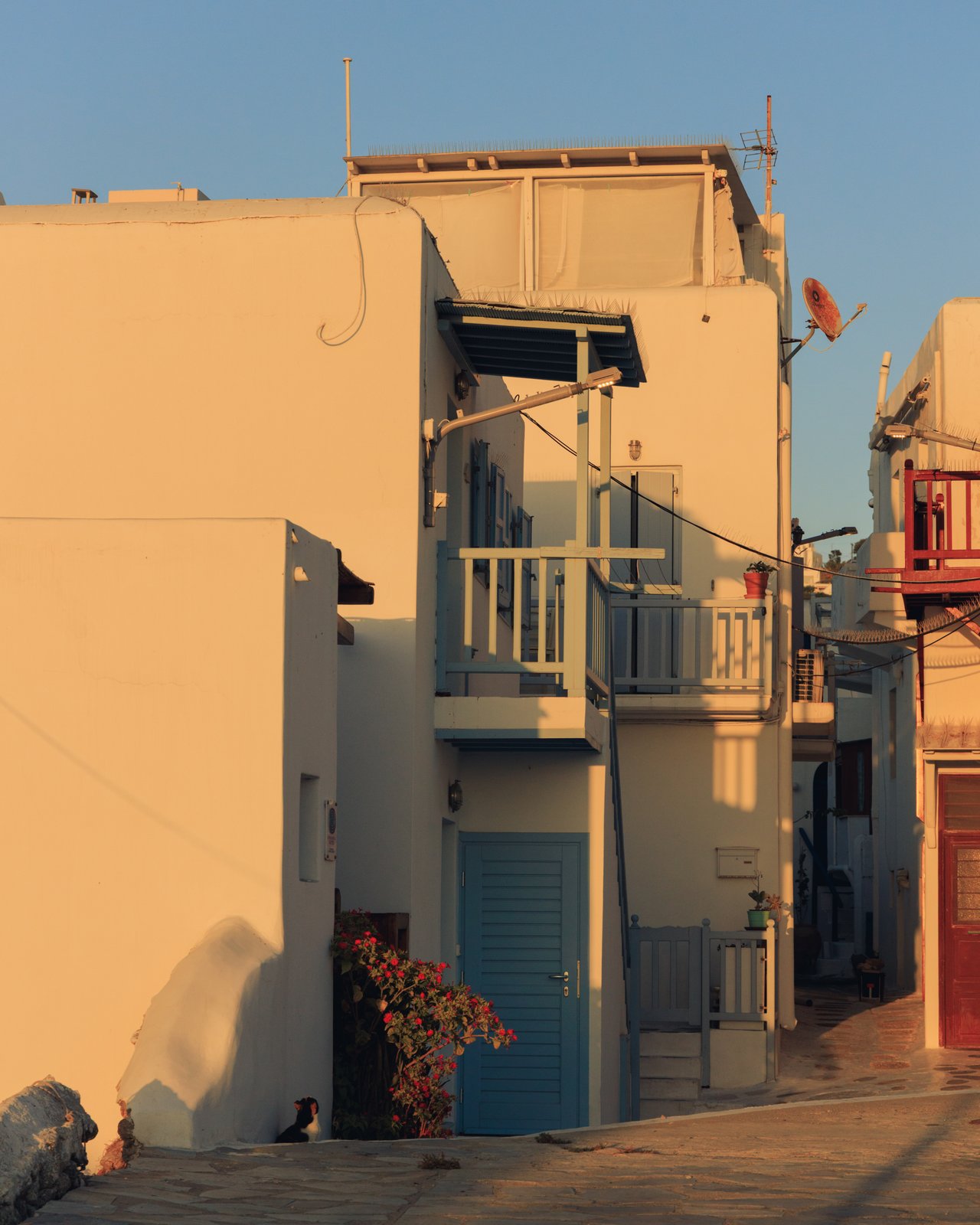 A whitewashed lane of Cycladic houses with blue doors at golden hour, Greece