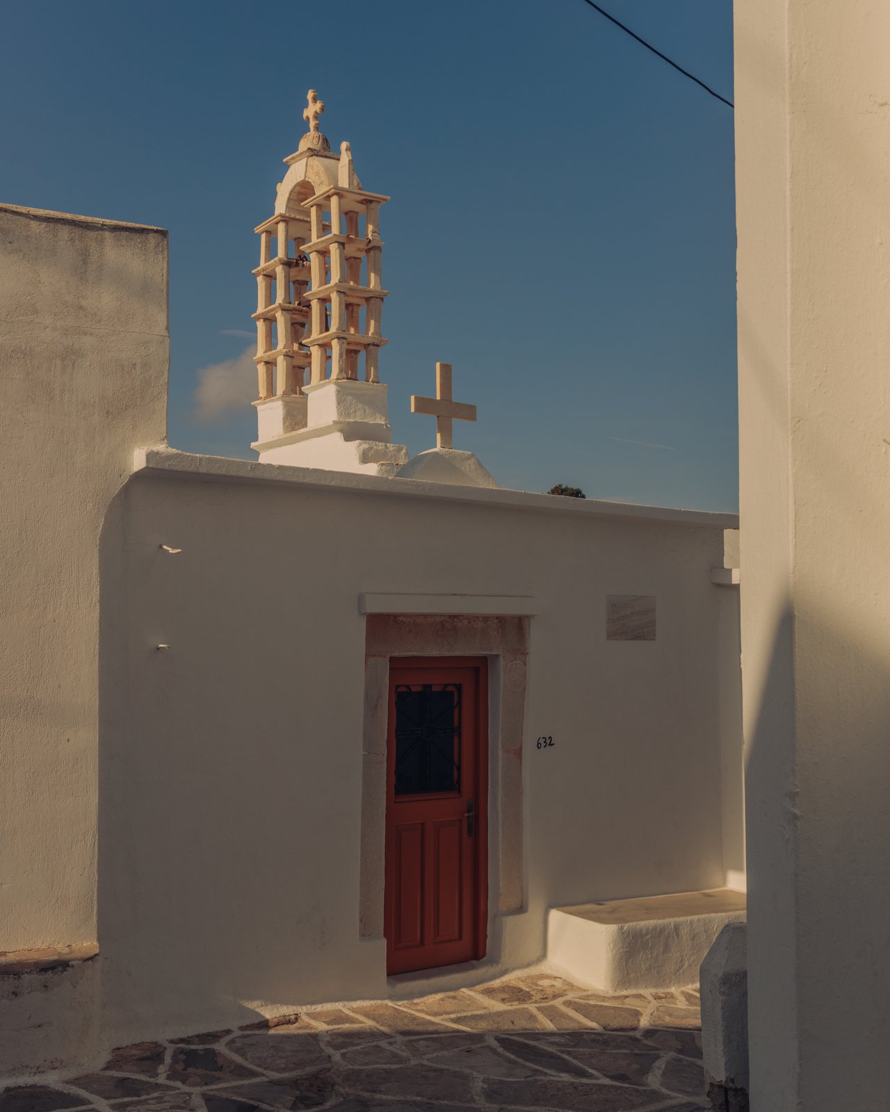 A whitewashed church with a stepped bell-cote and a red door, Greece