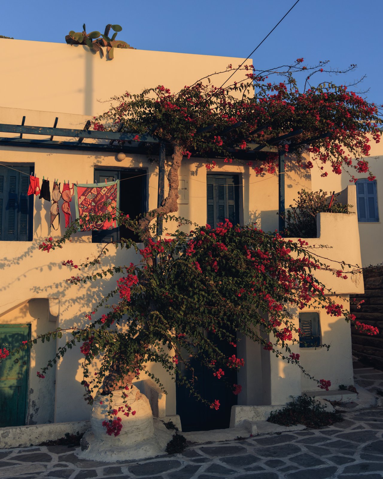 A whitewashed house cascading with pink bougainvillea over a cobbled lane, Greece