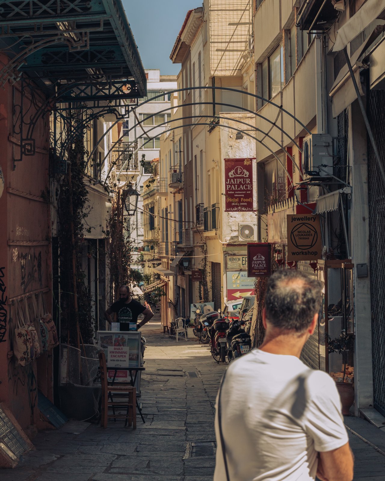 A Plaka street of shops and trellises, a man walking, Athens, Greece