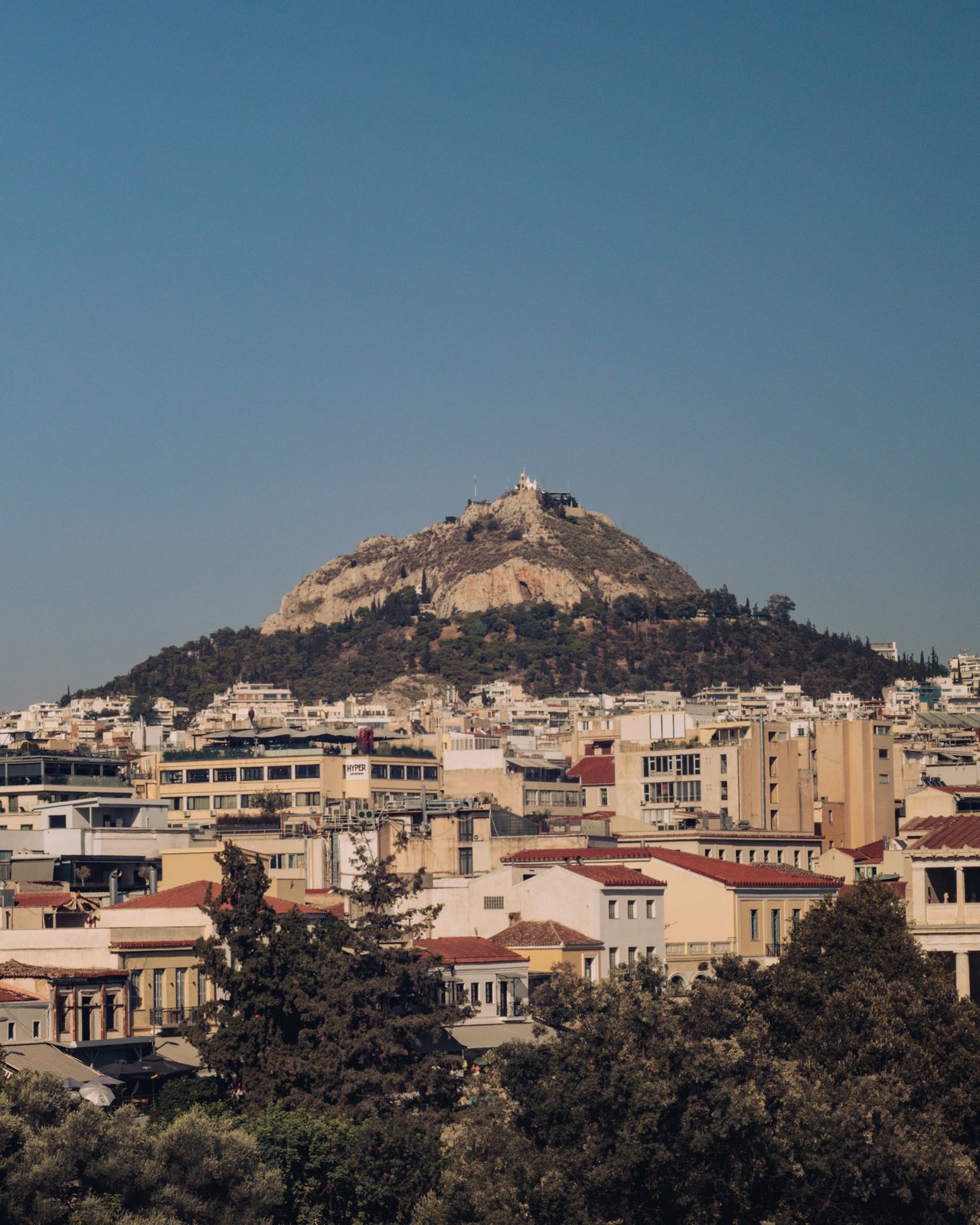 A view over Athens rooftops to Lycabettus Hill and its chapel, Greece