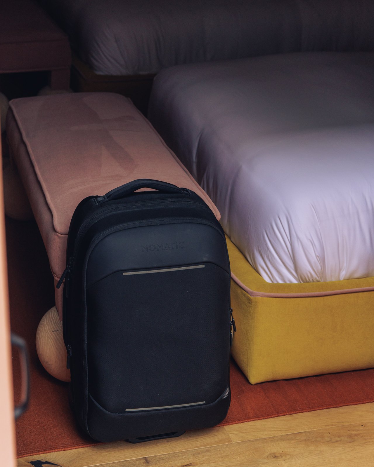A black suitcase beside a mustard-yellow bed base, Ignacia Guest House