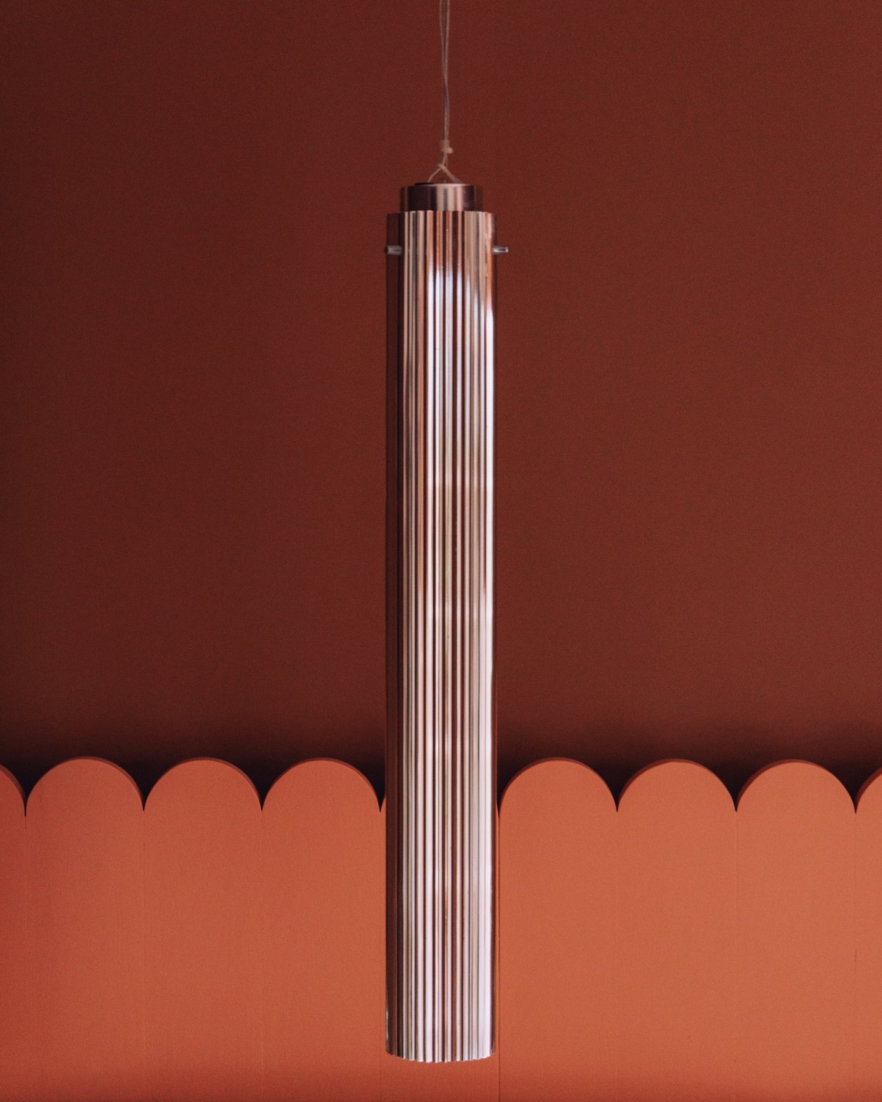 A fluted glass pendant light against a scallop-bordered terracotta wall, Ignacia Guest House