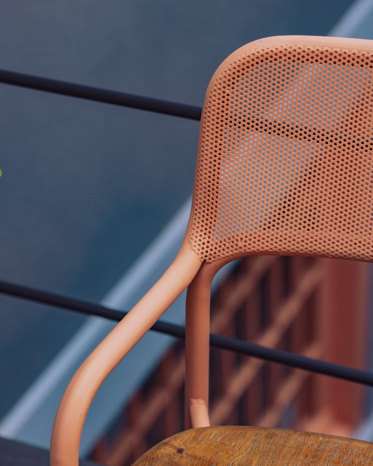 A close-up of a perforated pink metal chair by a railing, Ignacia Guest House