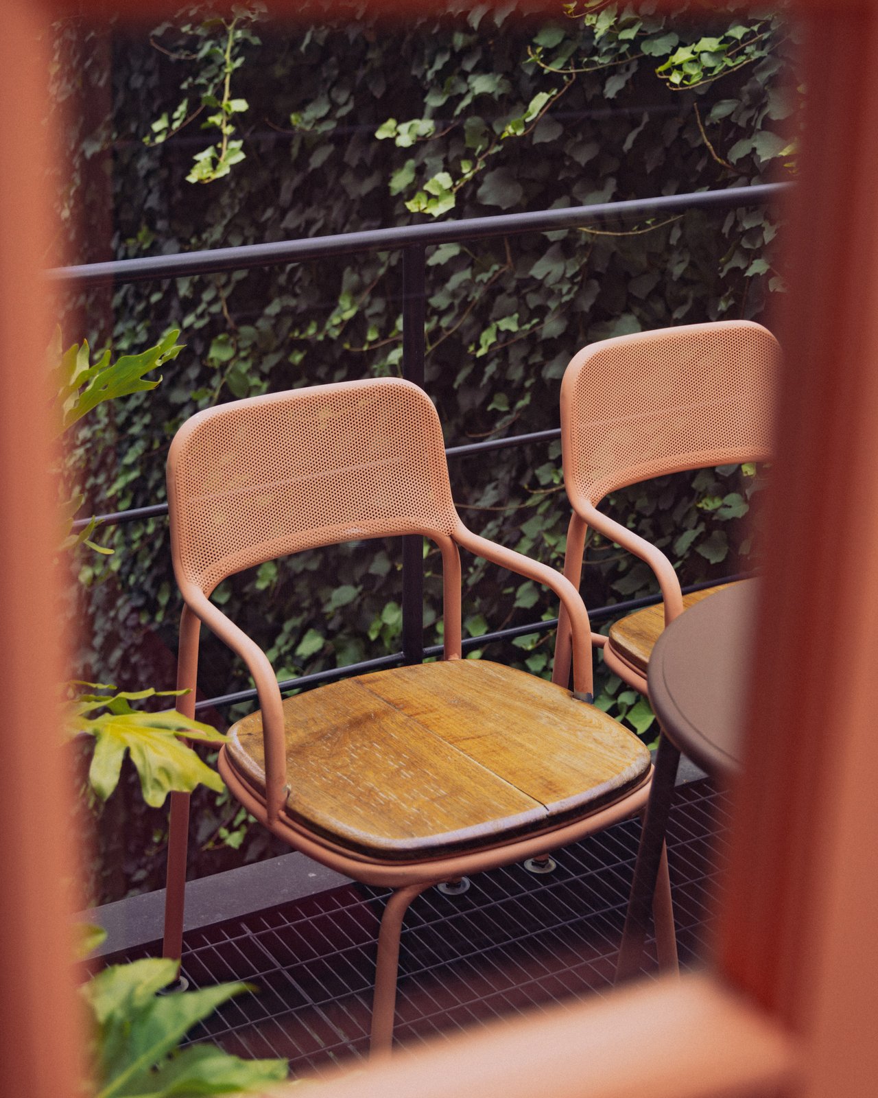 Pink metal chairs and a wood table on a balcony against an ivy-covered wall, Ignacia Guest House