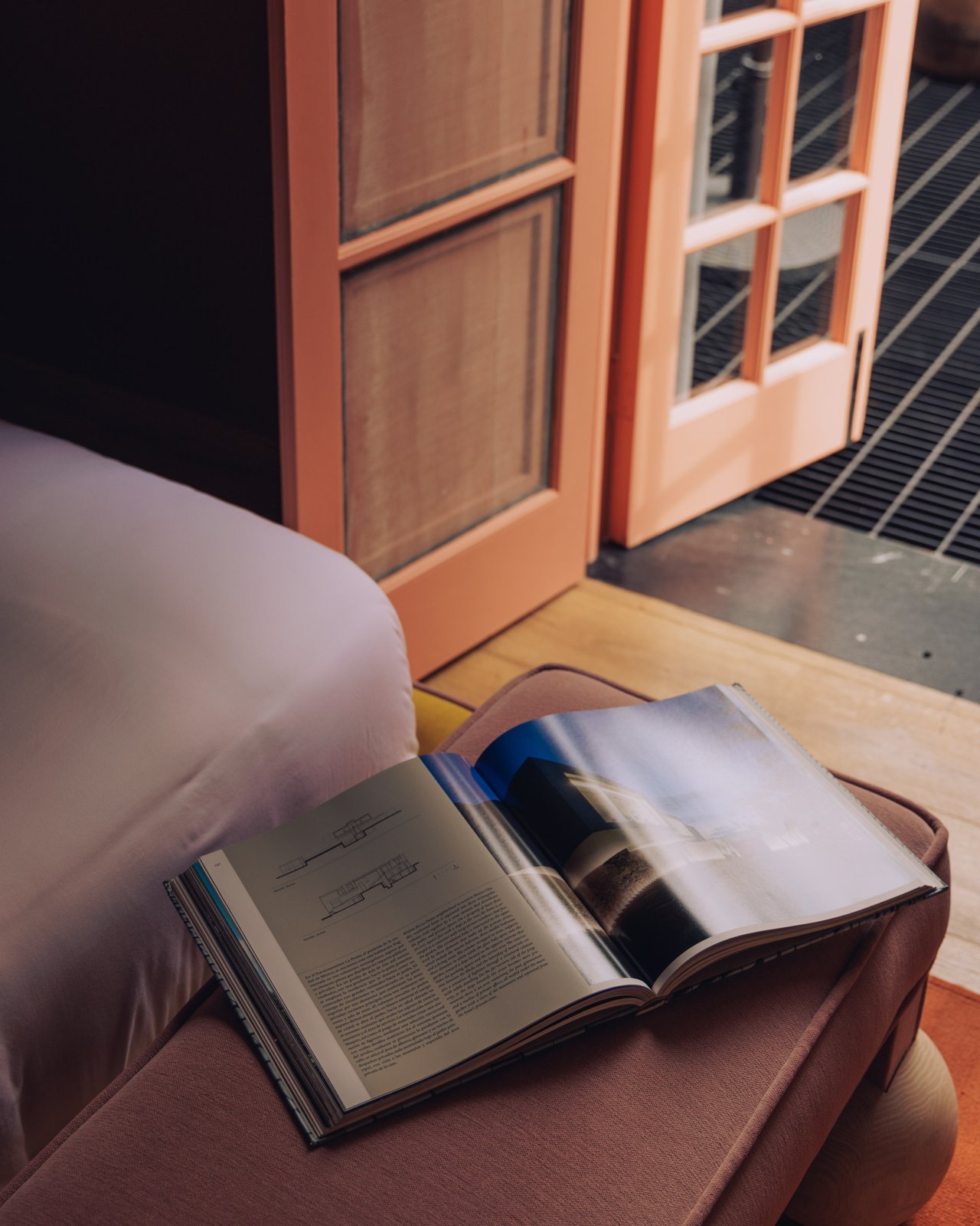 An open book on a bed by a window in a terracotta room, Ignacia Guest House