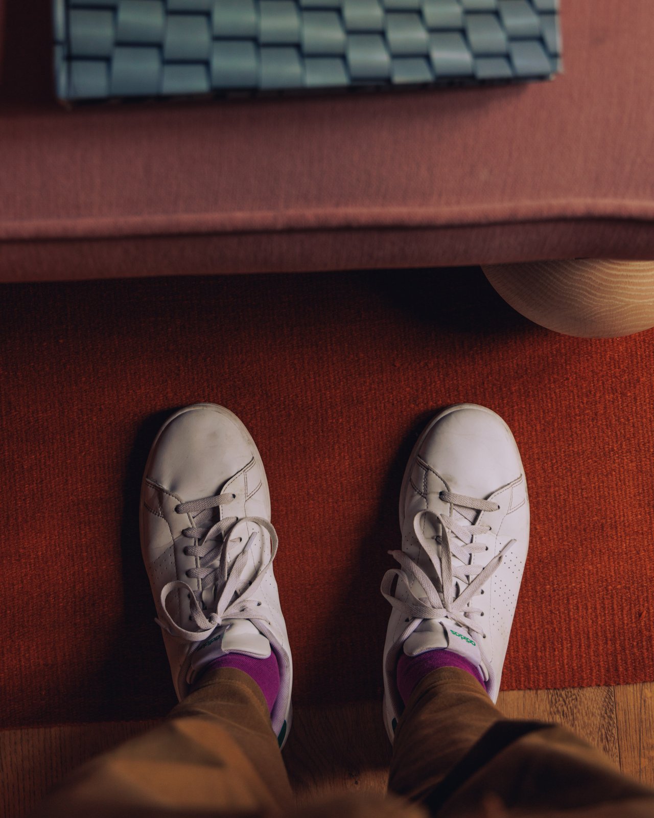 A top-down of white sneakers on a terracotta rug by a bench, Ignacia Guest House