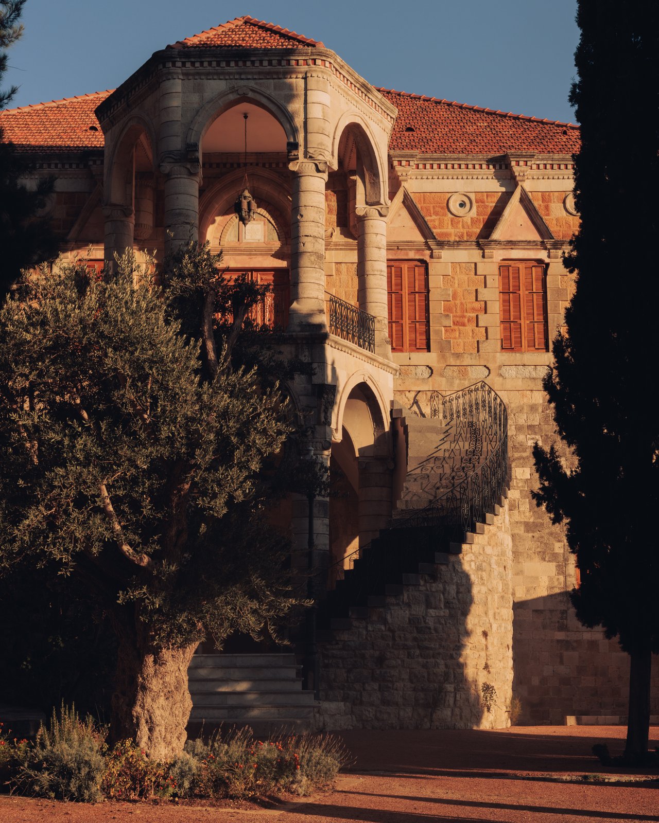 A portrait of a smiling bearded man in a grey T-shirt in a sunlit alley, Lebanon