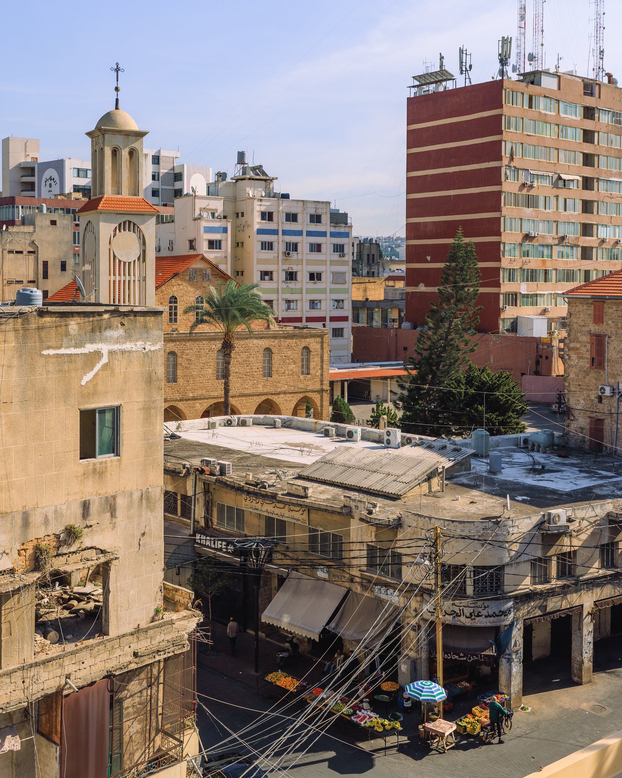 A hillside old-town lane with bougainvillea, a church tower above red-tile roofs, Lebanon