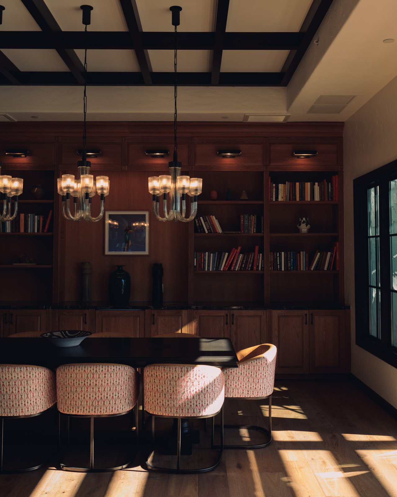 A wood-panelled library dining room with a chandelier and patterned banquette chairs at the Mar Monte Hotel