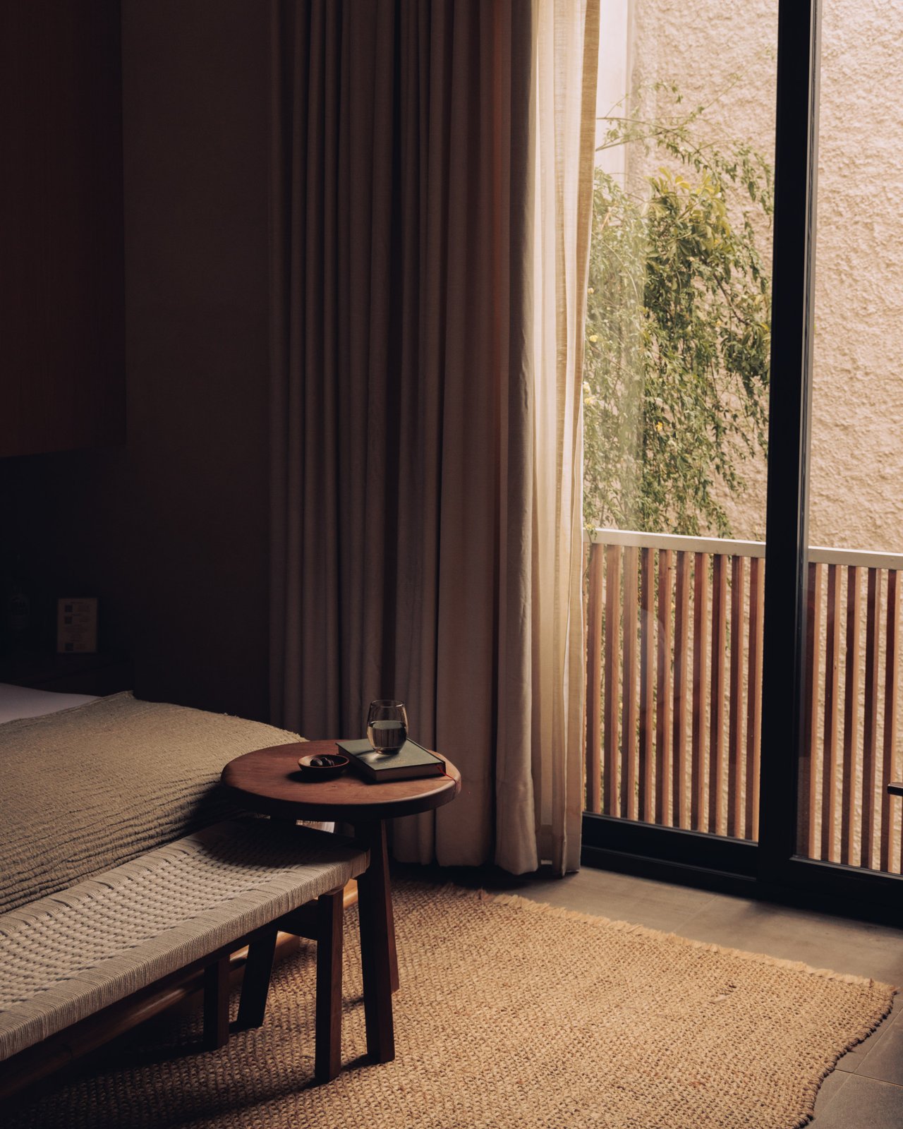 A warm wood door standing ajar in a plaster-walled corridor of the guest house