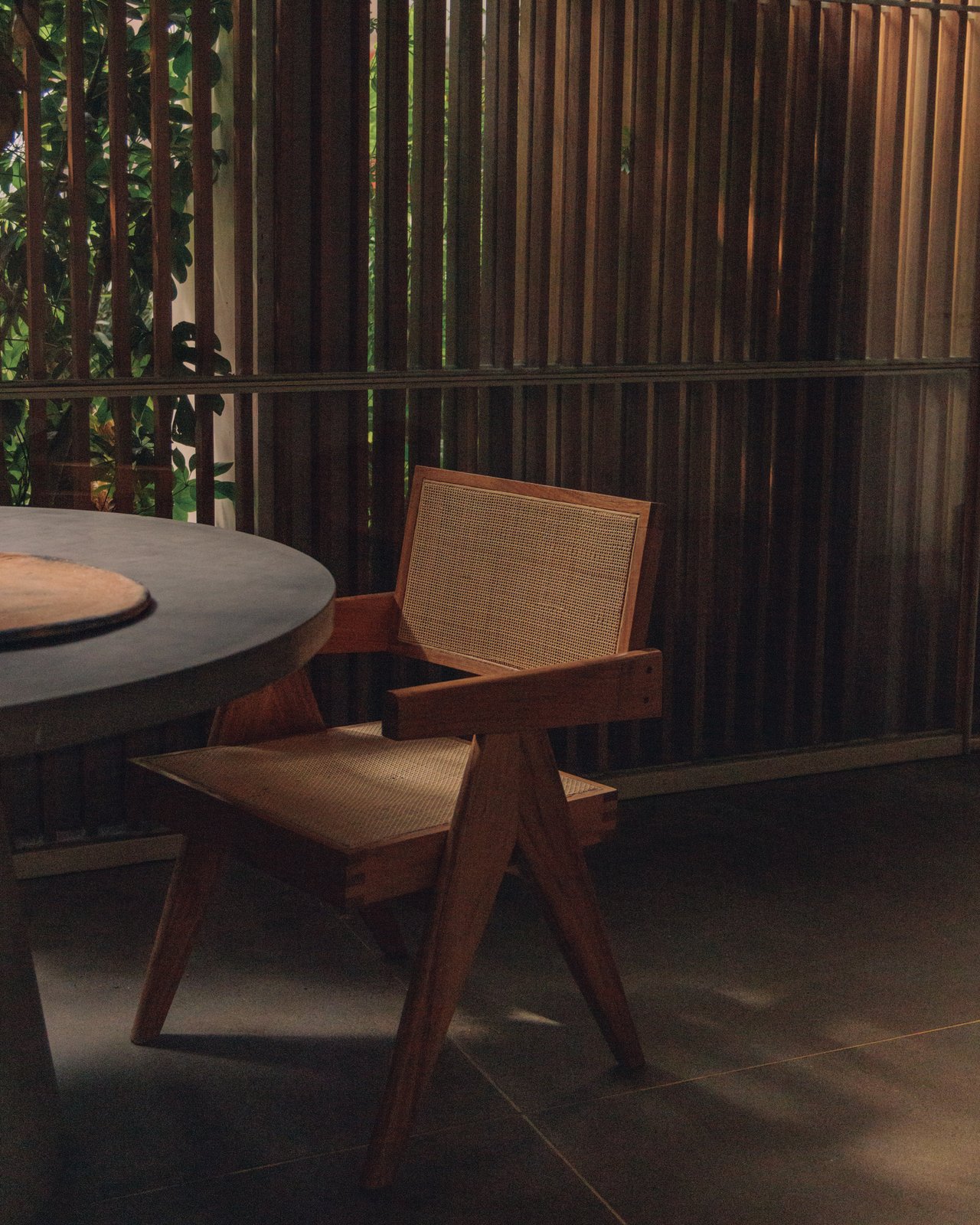 A made guest bed with a green throw and wood cabinetry, a suitcase resting on the floor