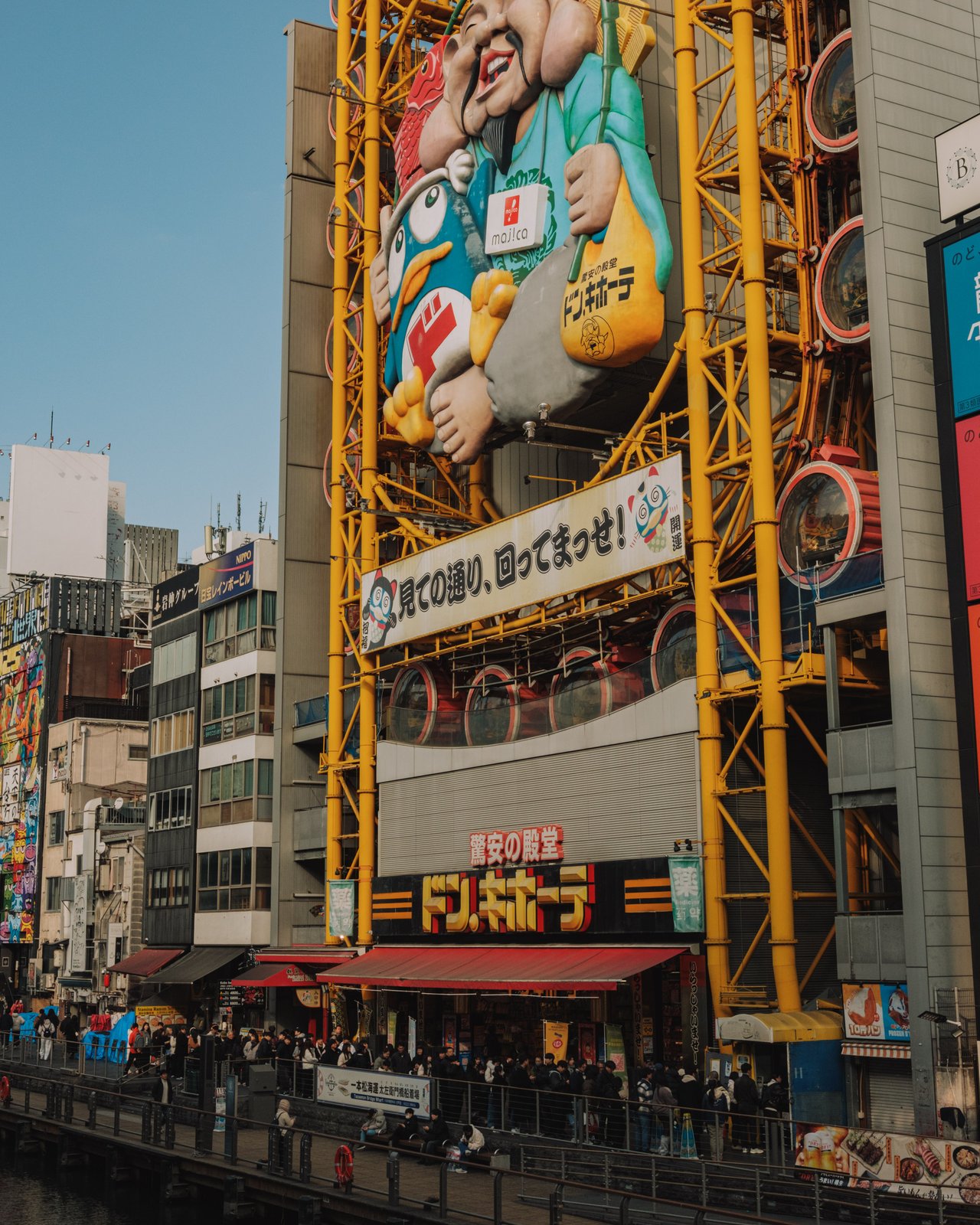 The Dotonbori canal crowded beneath giant billboards and a Ferris wheel, Osaka