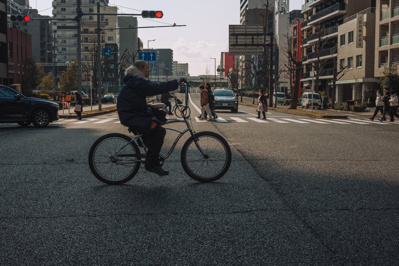 A cyclist crossing a wide city intersection, Osaka