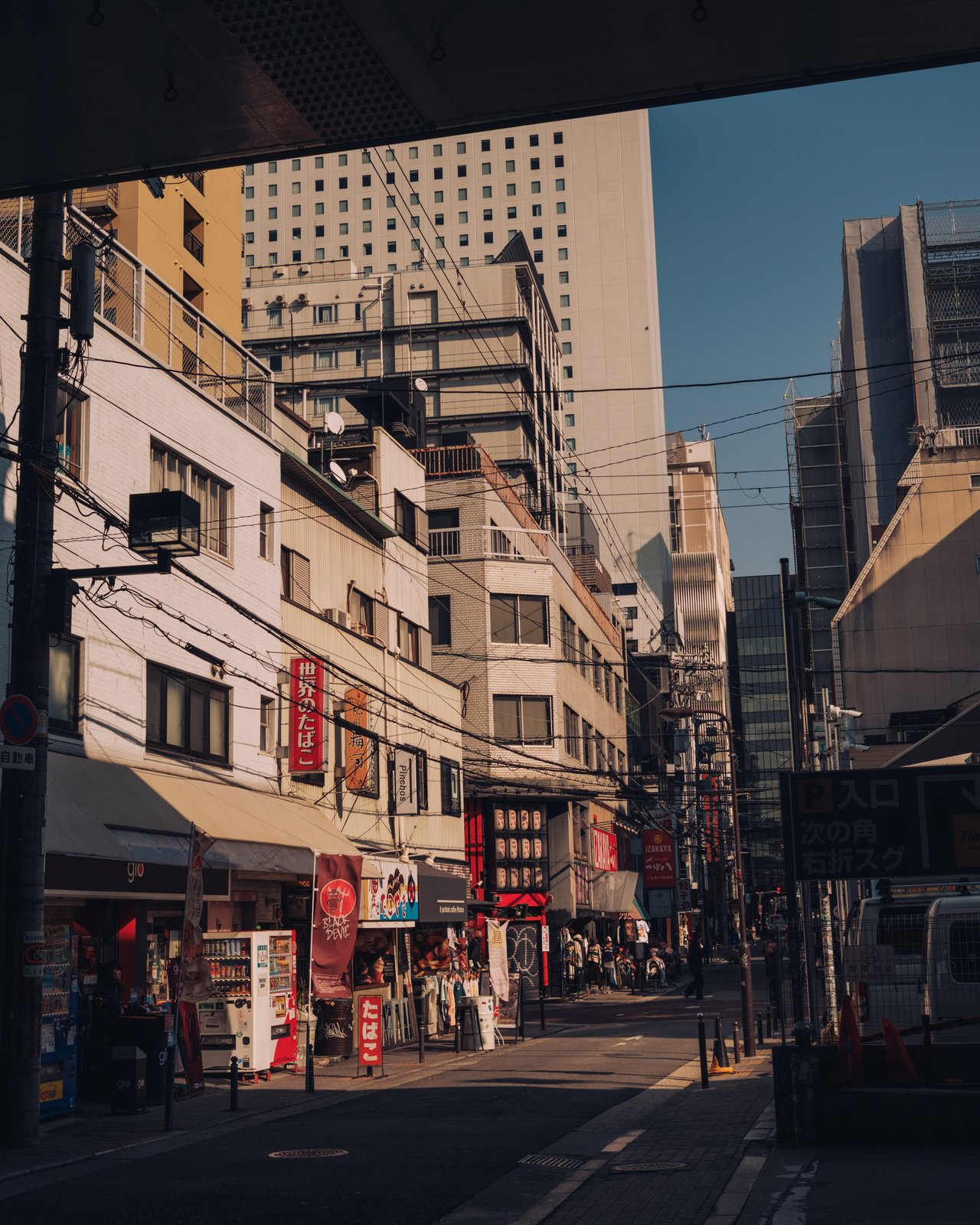 A downtown street of mixed old buildings and signage at golden hour, Osaka
