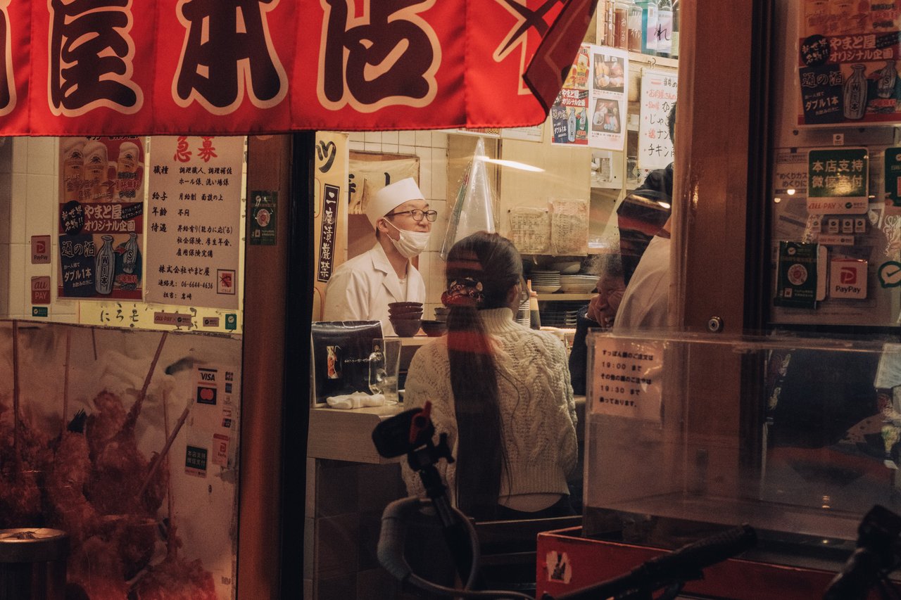 A chef behind the counter of a small restaurant seen through the window, Osaka