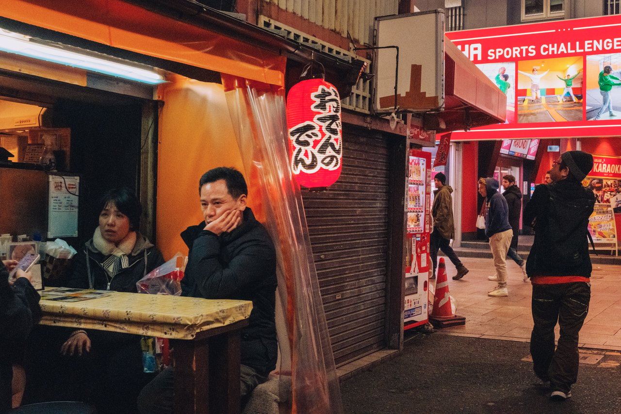 An oden street stall with red lanterns and seated customers, Shinsekai, Osaka