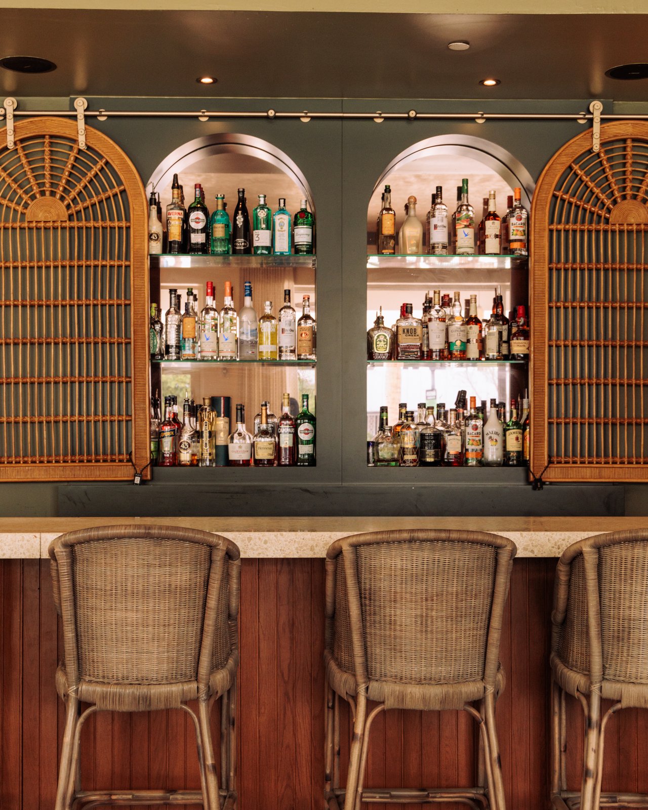 The back bar of arched cane cabinets and bottles above rattan stools, The Balfour Hotel