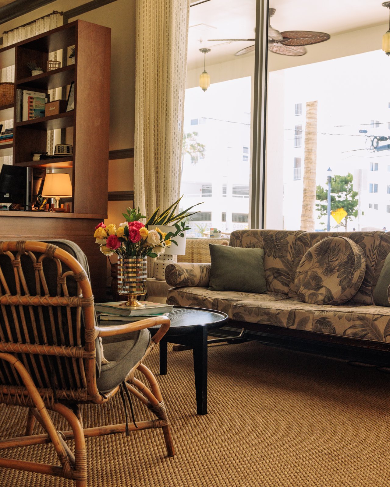 A lounge of rattan armchairs and a floral sofa with fresh flowers by the street windows, The Balfour Hotel