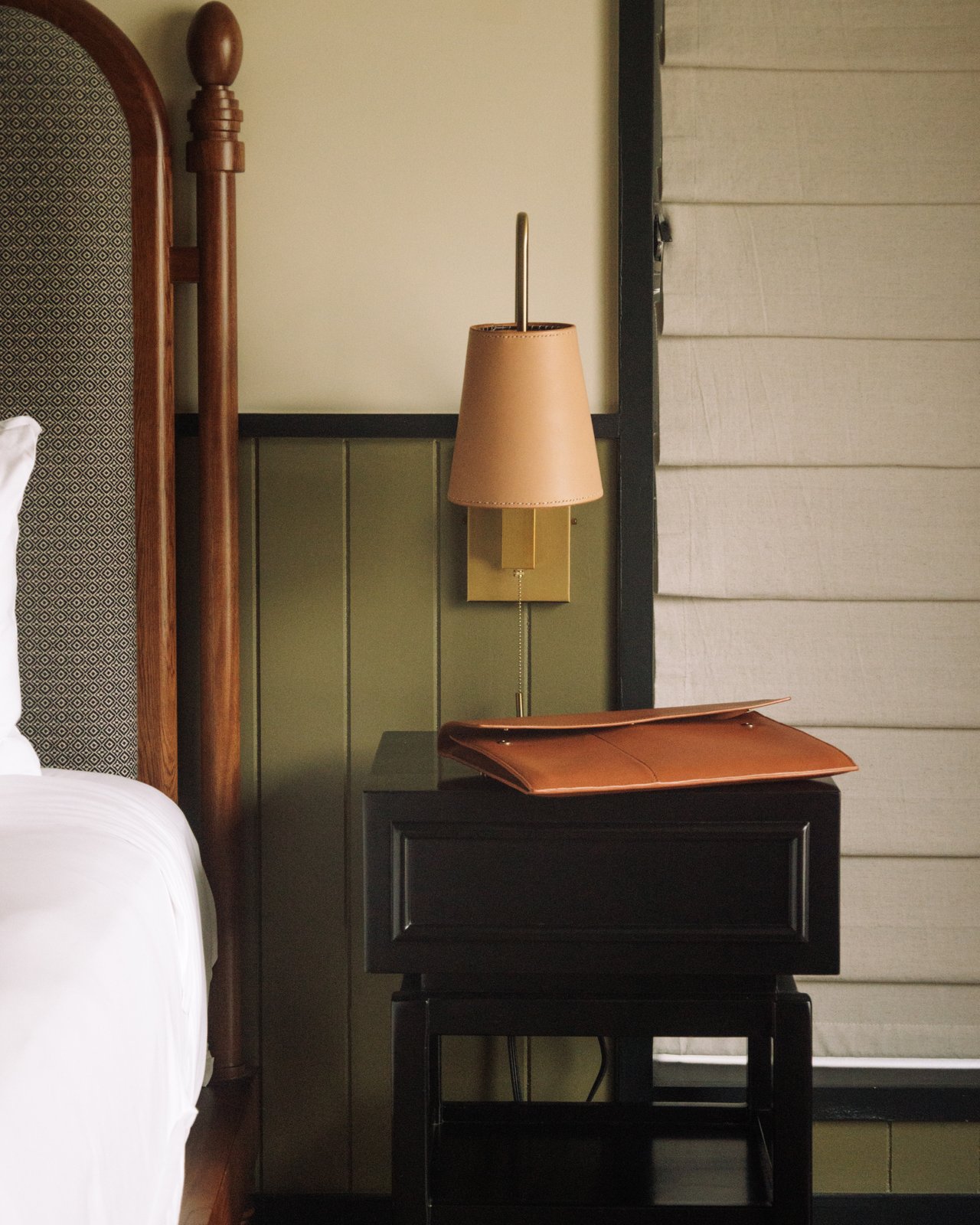 A guest-room detail — a four-poster bed, a shaded sconce and a leather tray on the nightstand, The Balfour Hotel