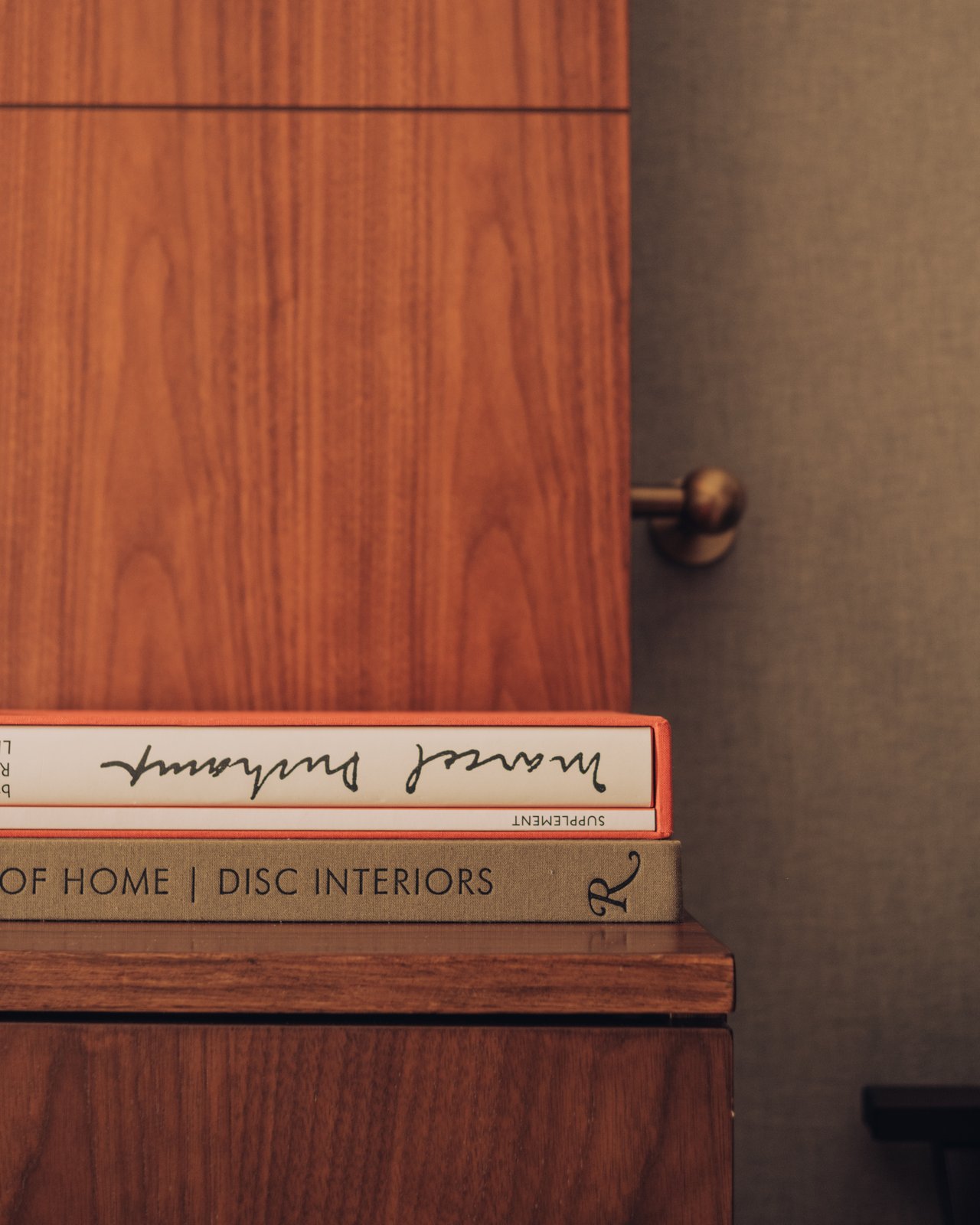 Design books stacked on a walnut credenza — the title card for the Global Ambassador film