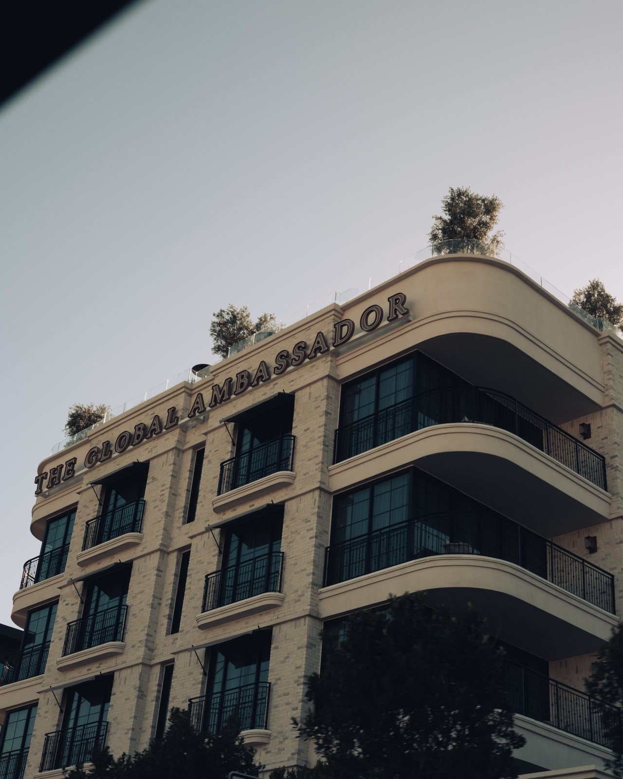 The Global Ambassador's curved streamline-modern facade and rooftop lettering against a clear sky