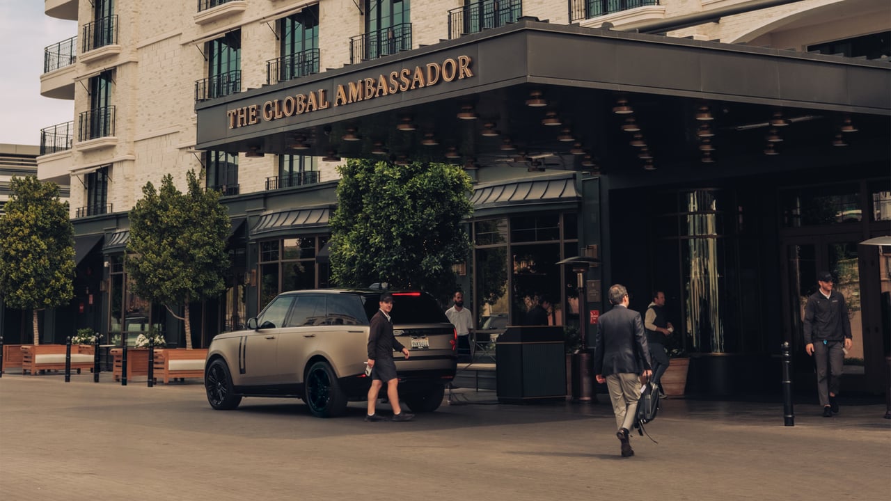 The Global Ambassador's porte-cochère — a Range Rover under the marquee as a valet and guests arrive, Phoenix