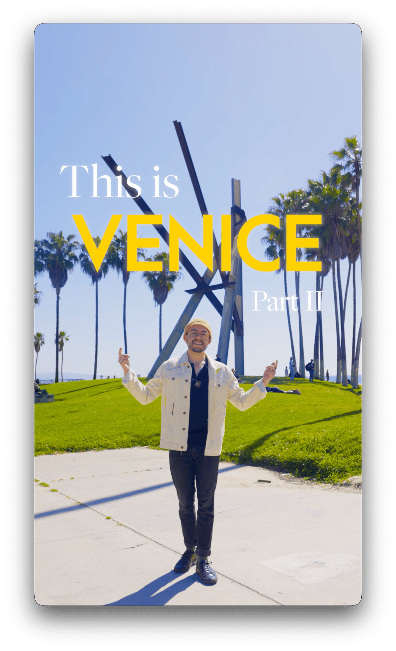 Title card: 'This is Venice, Part II' — a man on a grassy rise by the kinetic sculpture, Venice Beach