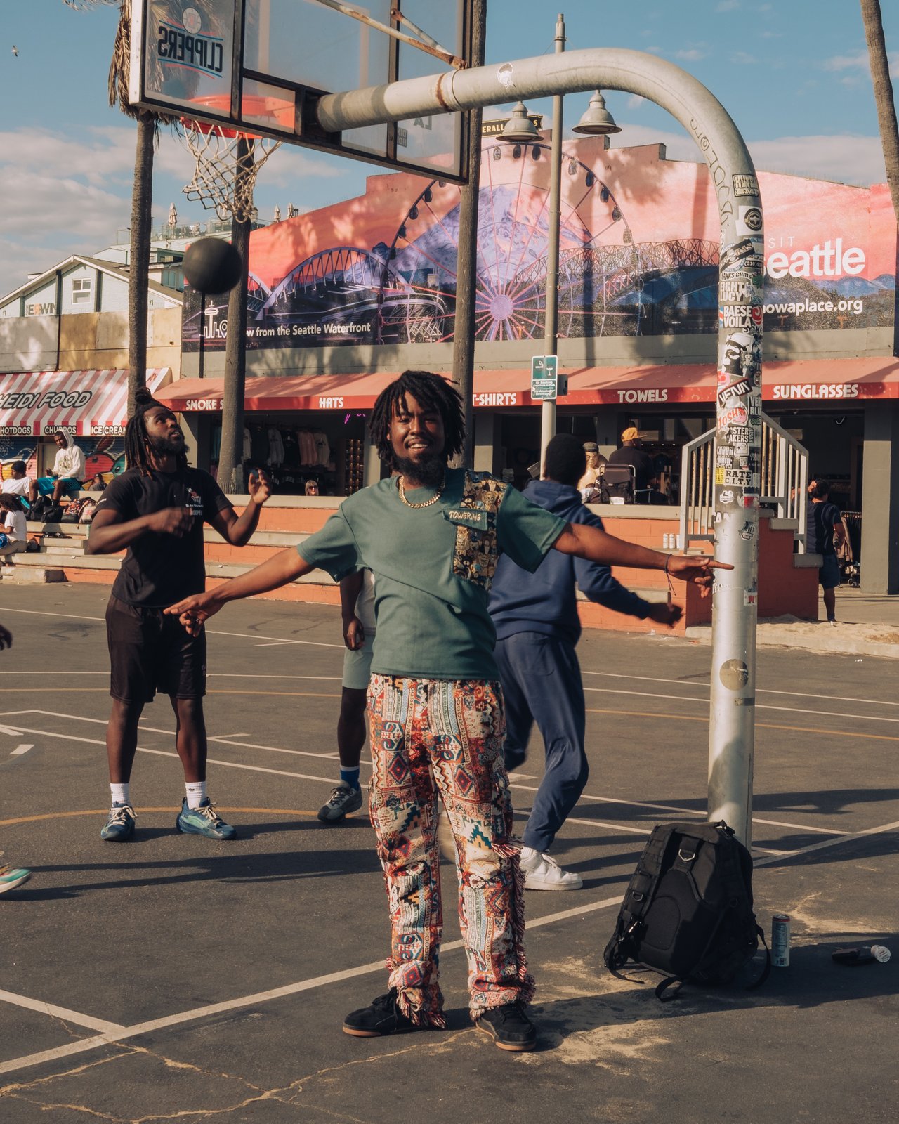 Young men on the Venice Beach basketball courts by the boardwalk shops
