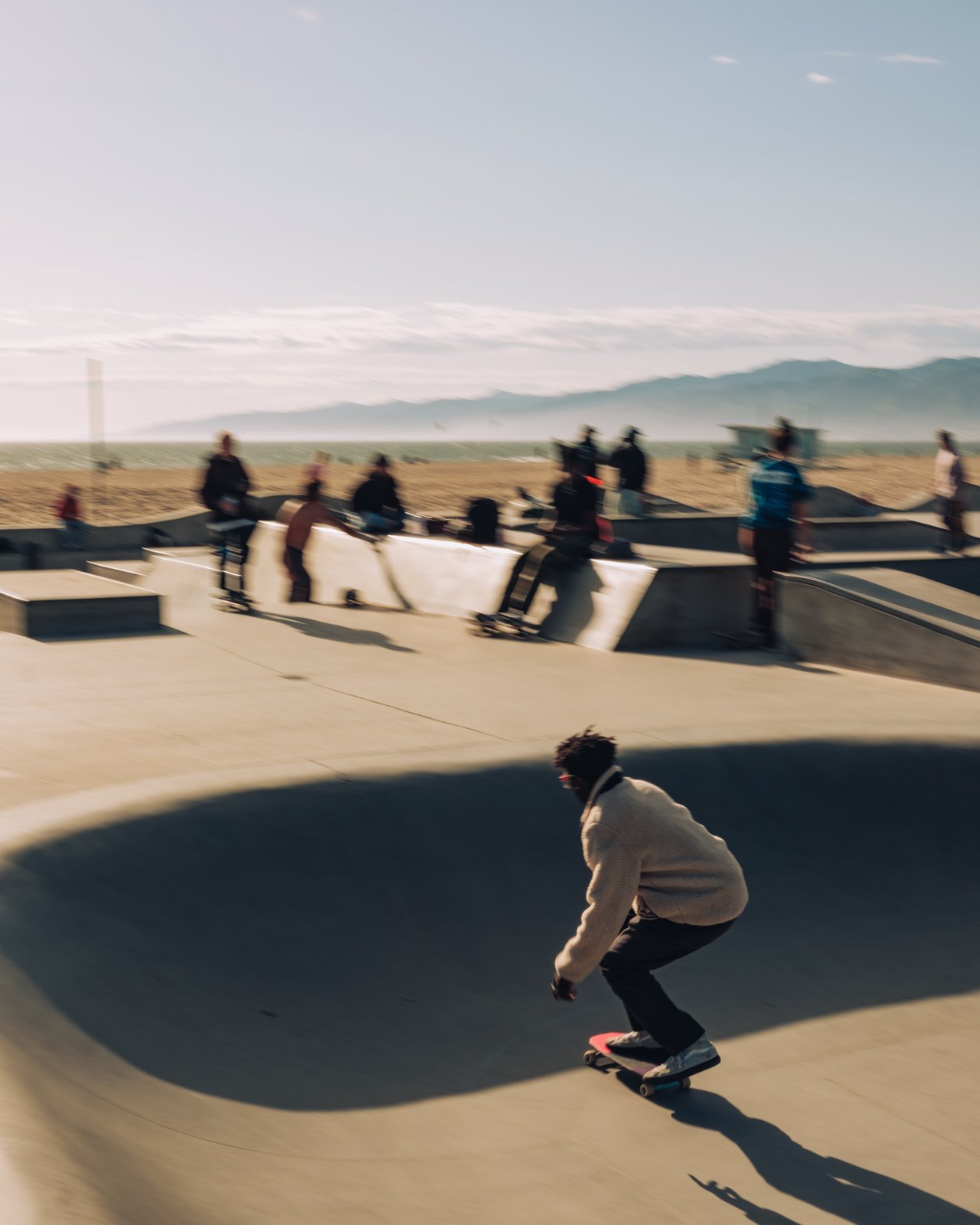 Skaters at the Venice Beach skate park with the beach beyond