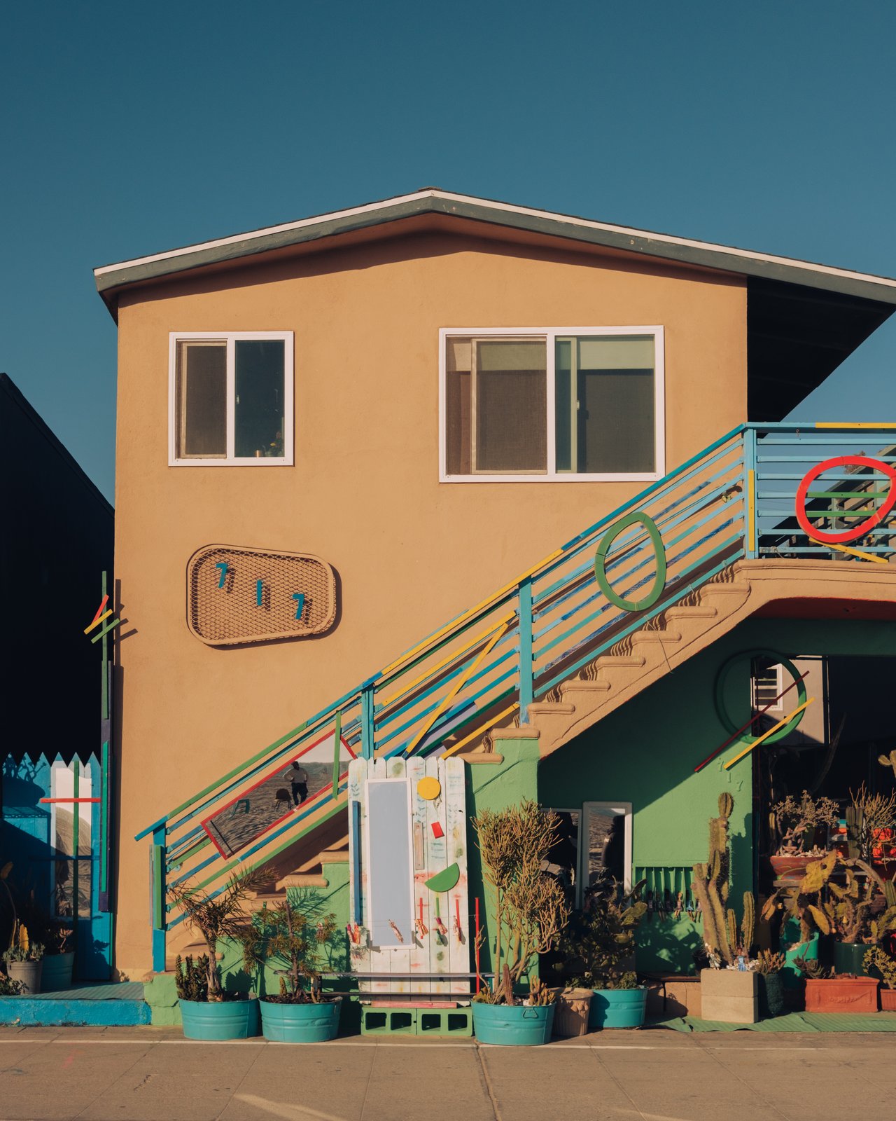 A colourful orange-and-teal Venice house with an exterior staircase and plants