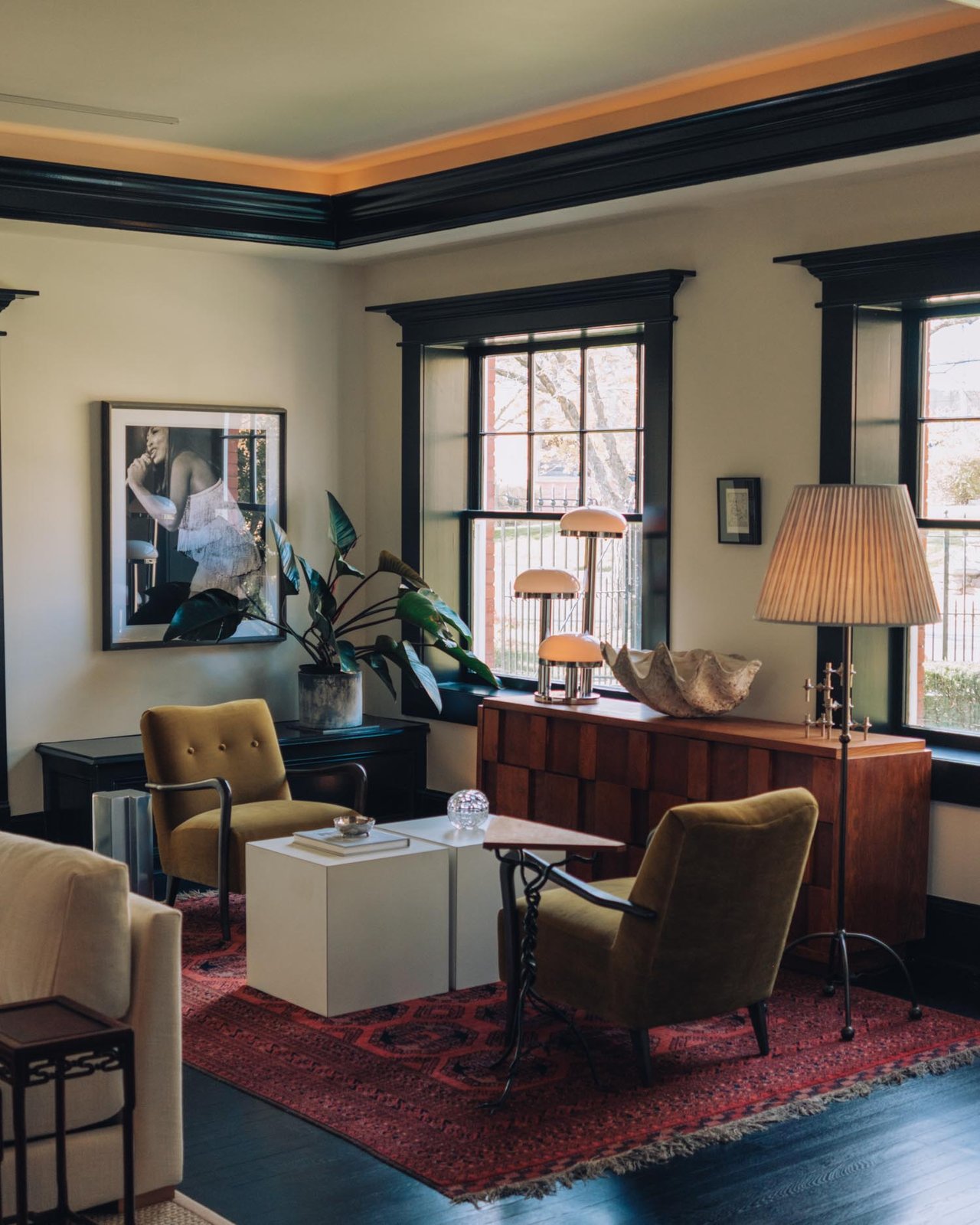 A hotel sitting room with mid-century chairs, a Persian rug and lamplight, Kansas City