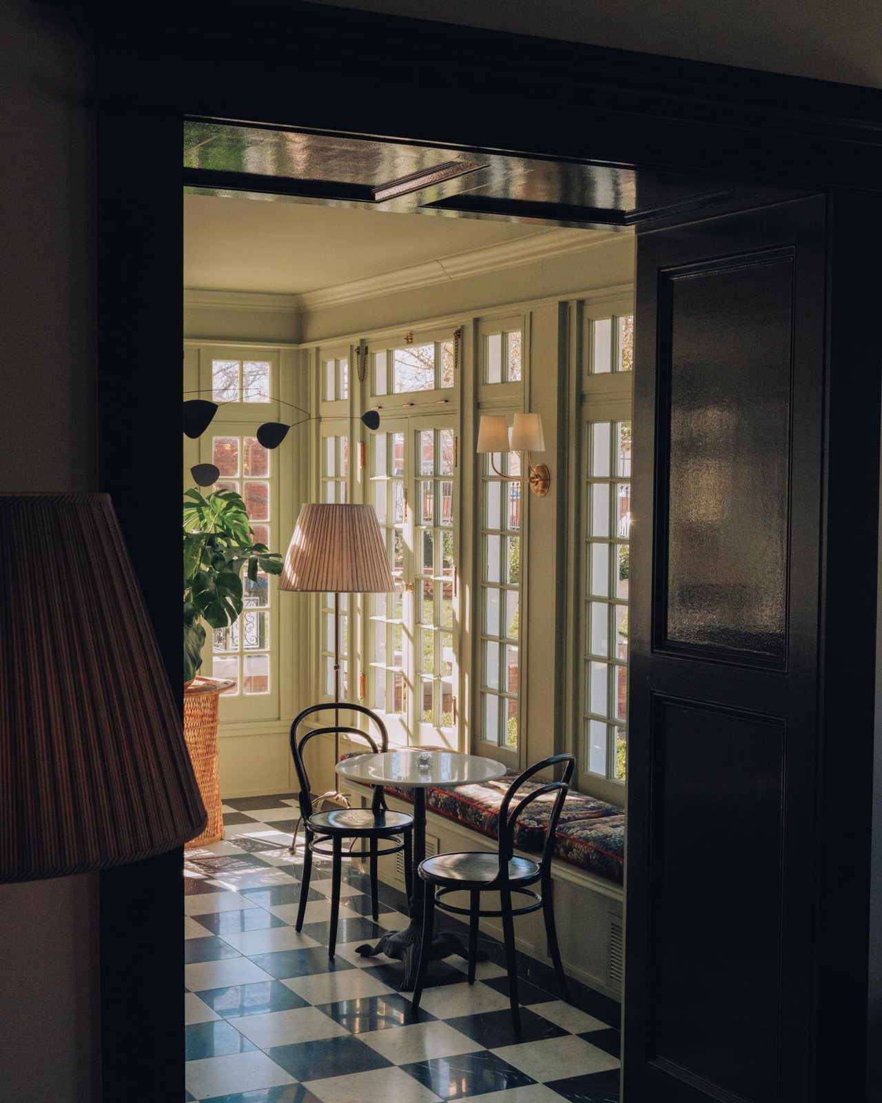 A checkered-floor sunroom with bentwood chairs and a lamp, Kansas City