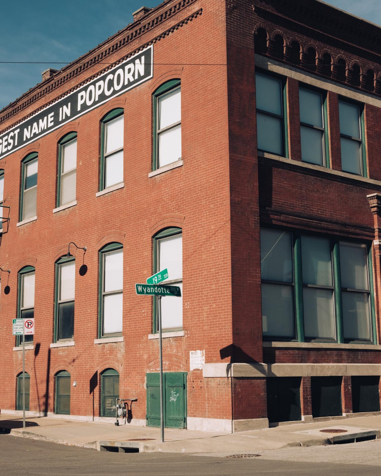 A historic red-brick building with a popcorn-company sign at a Wyandotte Street corner, Kansas City