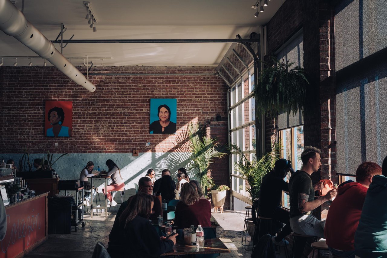 A lively brick-walled loft cafe full of people at golden hour, Kansas City