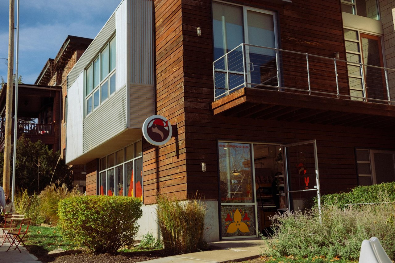 A modern wood-clad building with a rooster sign and landscaping, Kansas City