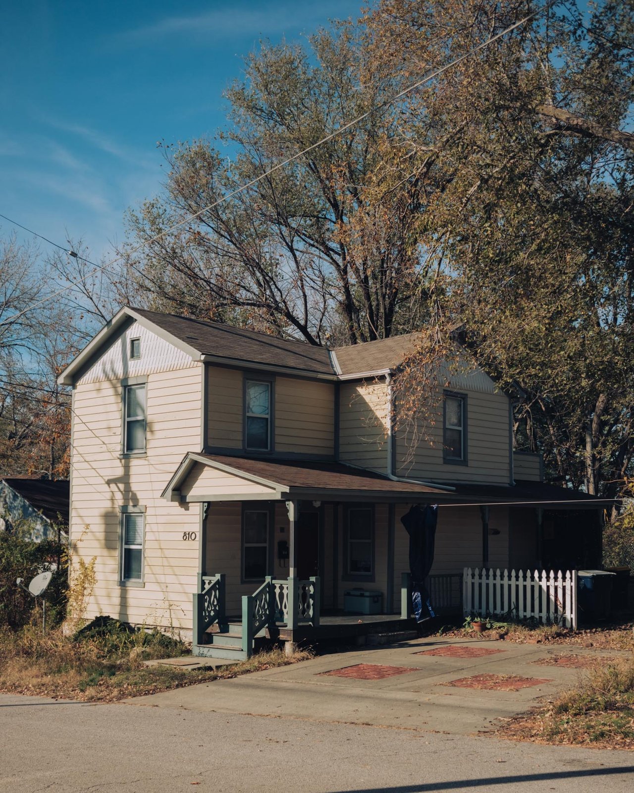 A two-storey clapboard house with a porch on an autumn street, Kansas City