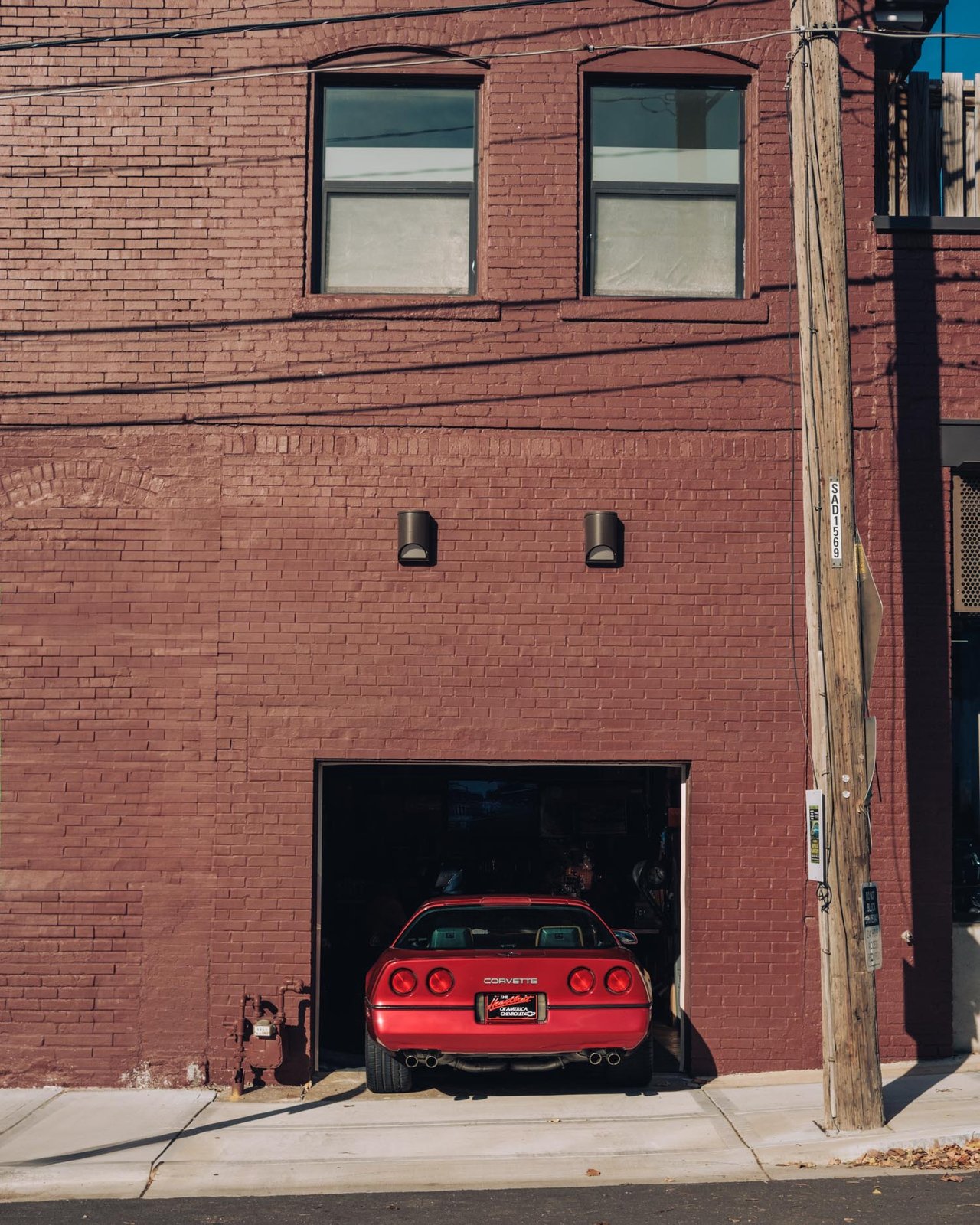 A red Chevrolet Corvette parked in a brick building's garage off the alley, Kansas City
