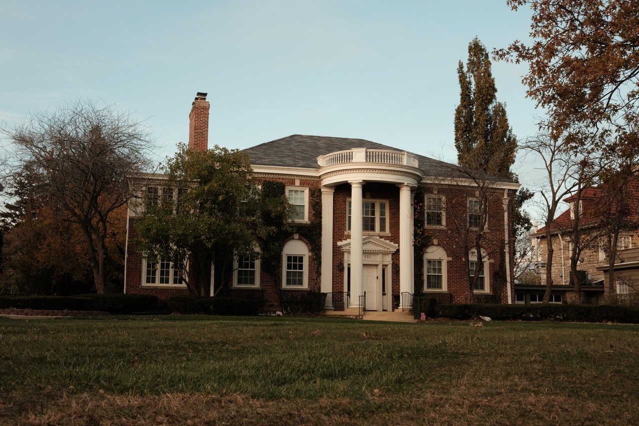 A stately brick Colonial mansion with white columns on a lawn, Kansas City