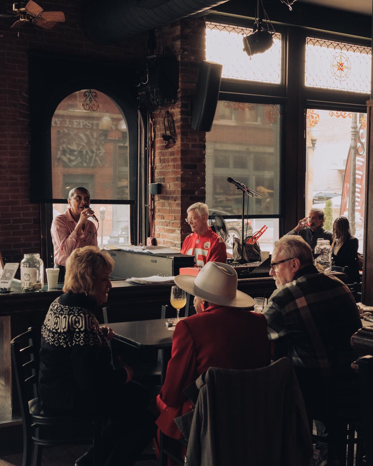 A warm brick-walled restaurant full of diners by the windows at golden hour, Kansas City