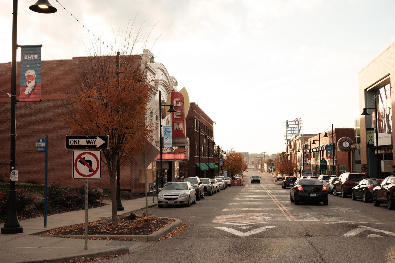 A one-way street of brick buildings and parked cars at golden hour, Kansas City