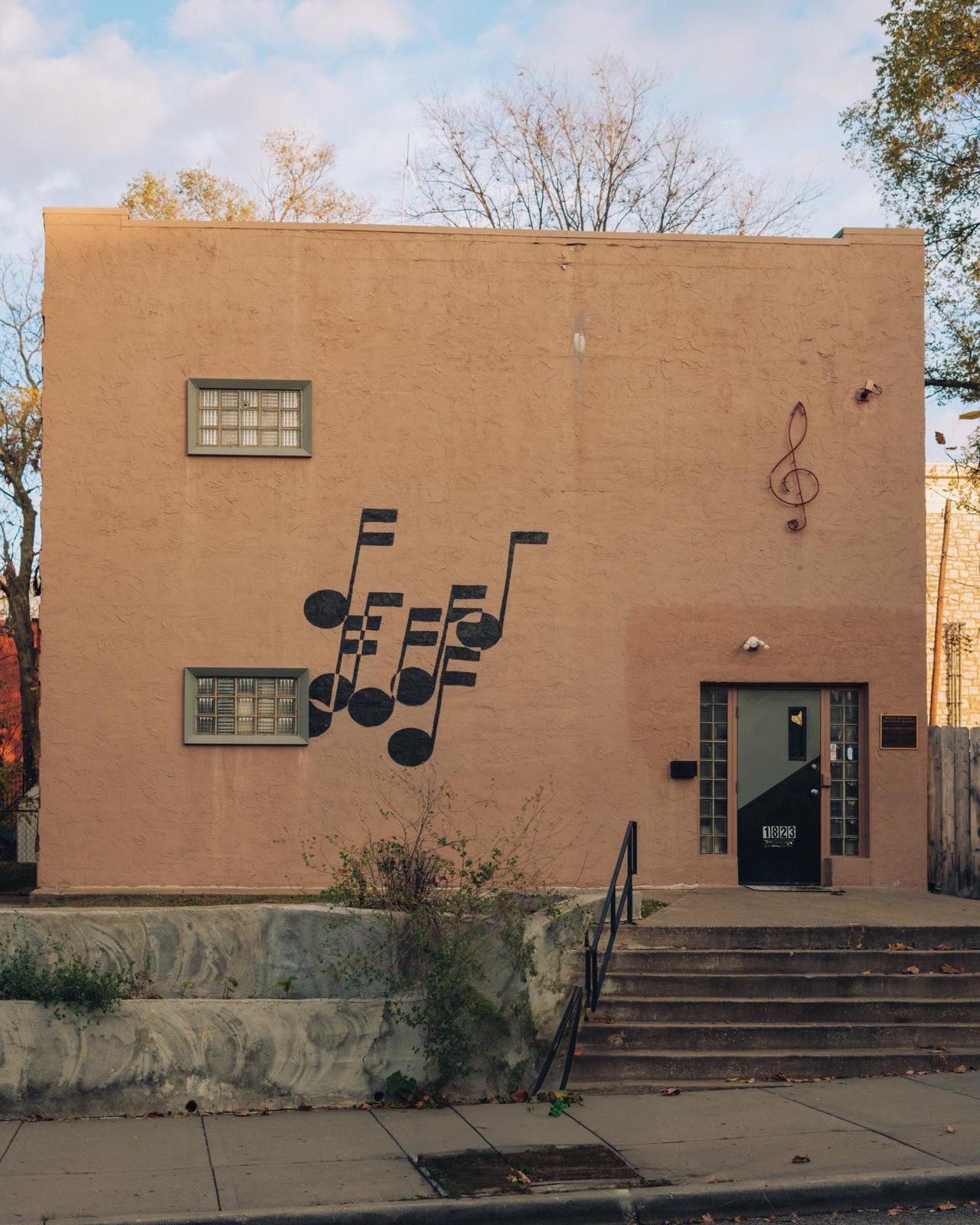 A stucco building painted with musical notes and a treble clef, steps to a green door, 18th & Vine, Kansas City