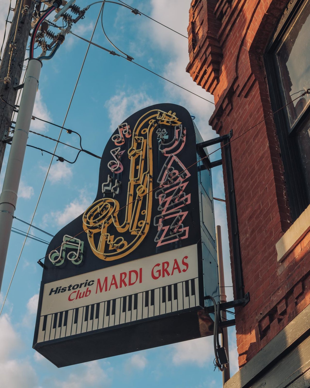 The piano-and-sax sign of the Historic Club Mardi Gras against a brick wall, 18th & Vine, Kansas City