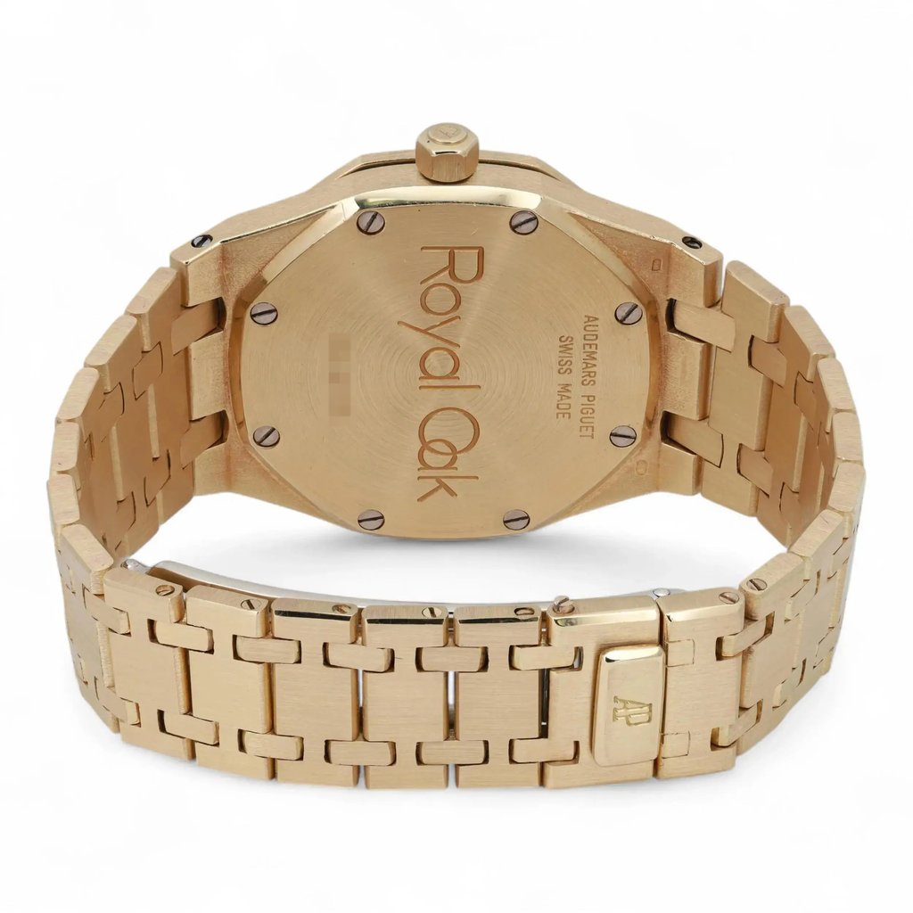 An image of a pre-owned Audemars Piguet women's wristwatch, prominently displaying the back view. The watch is positioned at a slight angle, facing upwards to reveal the "Royal Oak" engraving on the case back. The yellow gold bracelet, featuring a series of interlocking links, extends outward, filling the frame from a medium distance, showcasing its luxurious design and craftsmanship.