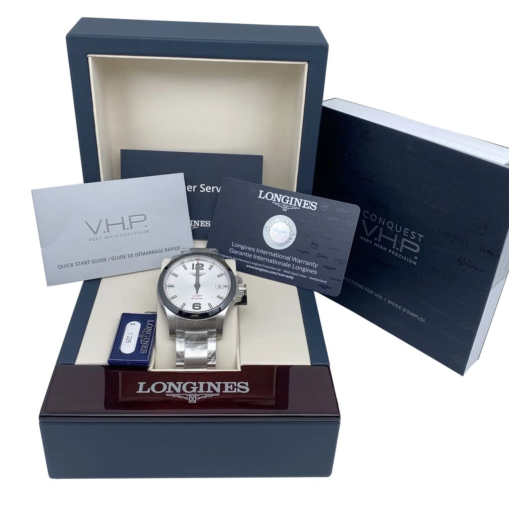 An image of a new wristwatch displayed in its open box, with accompanying documents and packaging. The watch, featuring a silver band and white dial, is positioned centrally in the foreground. To the left and right, warranty cards and guides are visible, adding context to the product's presentation. The background shows the box lid angled slightly open, revealing the brand name.